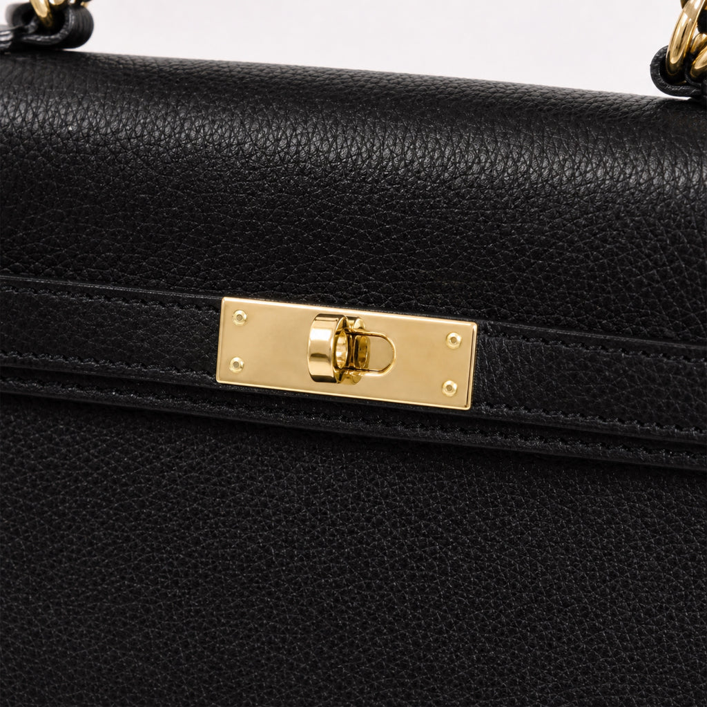 Czarny torebka skórzana kuferek z klapką i paskiem crossbody, detal materiału