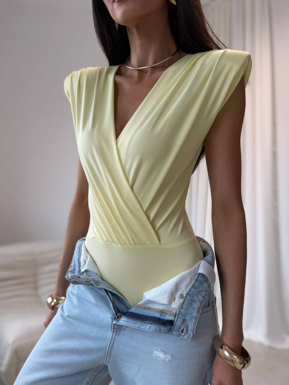 Żółty wariant body kopertowego z różą 3D, sylwetka w jeansach