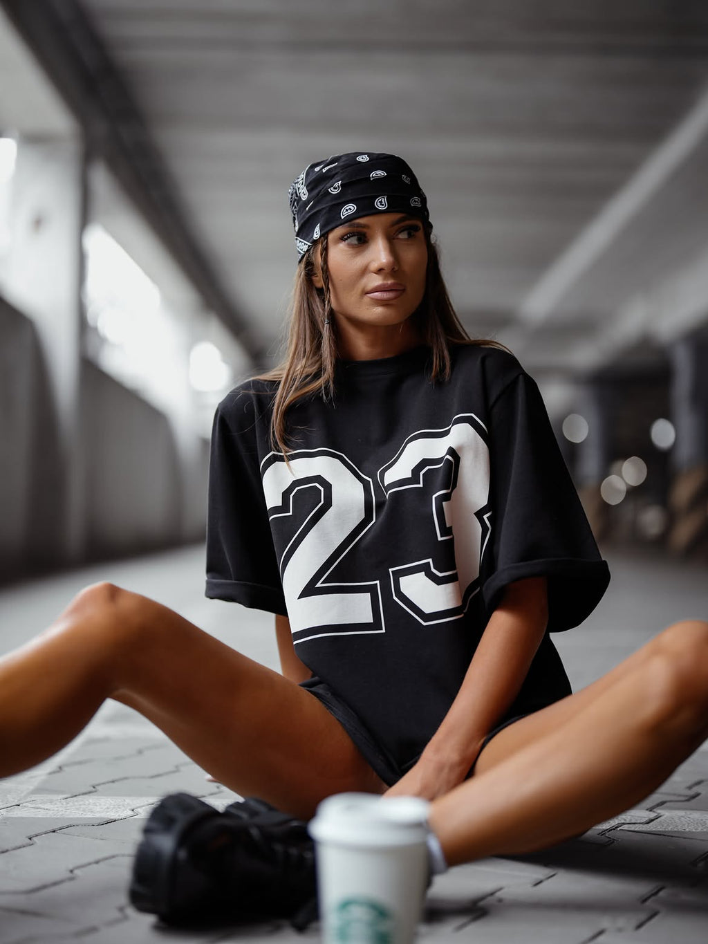 Czarny — t-shirt oversize z numerem 23, ujęcie siedzące z kubkiem