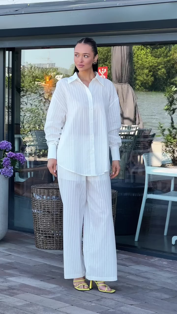 Biały komplet - koszula oversize i szerokie spodnie na modelce, prezentacja w ruchu