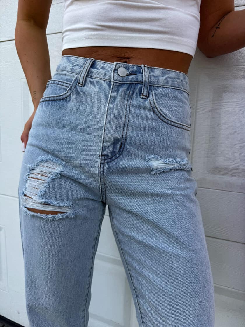 Jasnoniebieski jeansy mom fit, detal pasa i przetarć