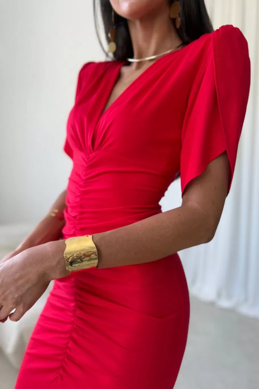 Czerwony wariant sukienki midi, detal kopertowego dekoltu